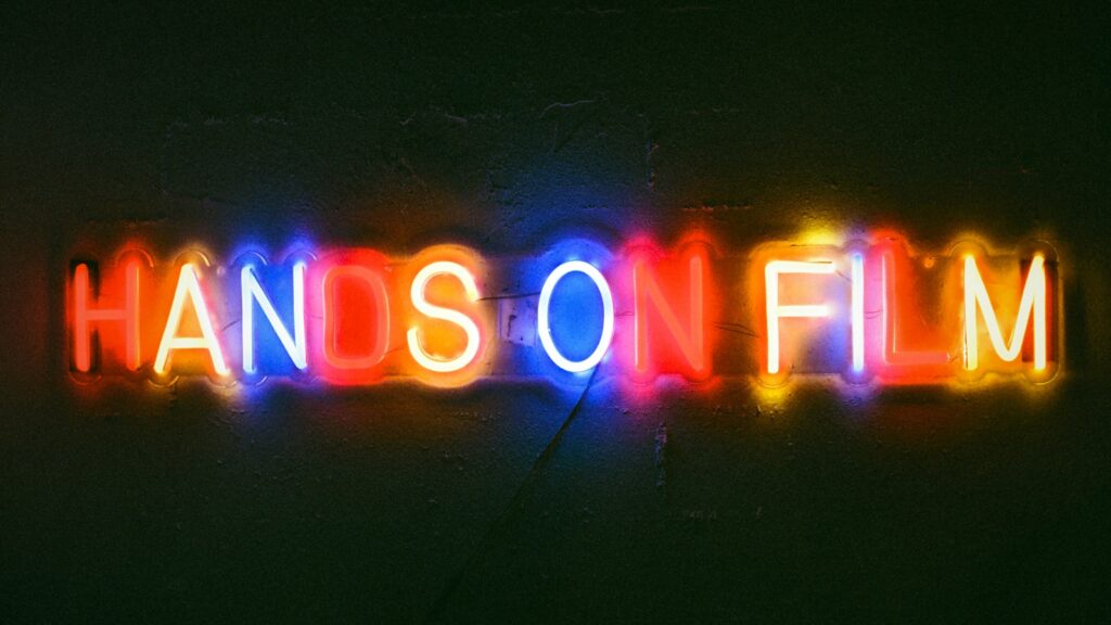 Neon sign reads "hands on film".