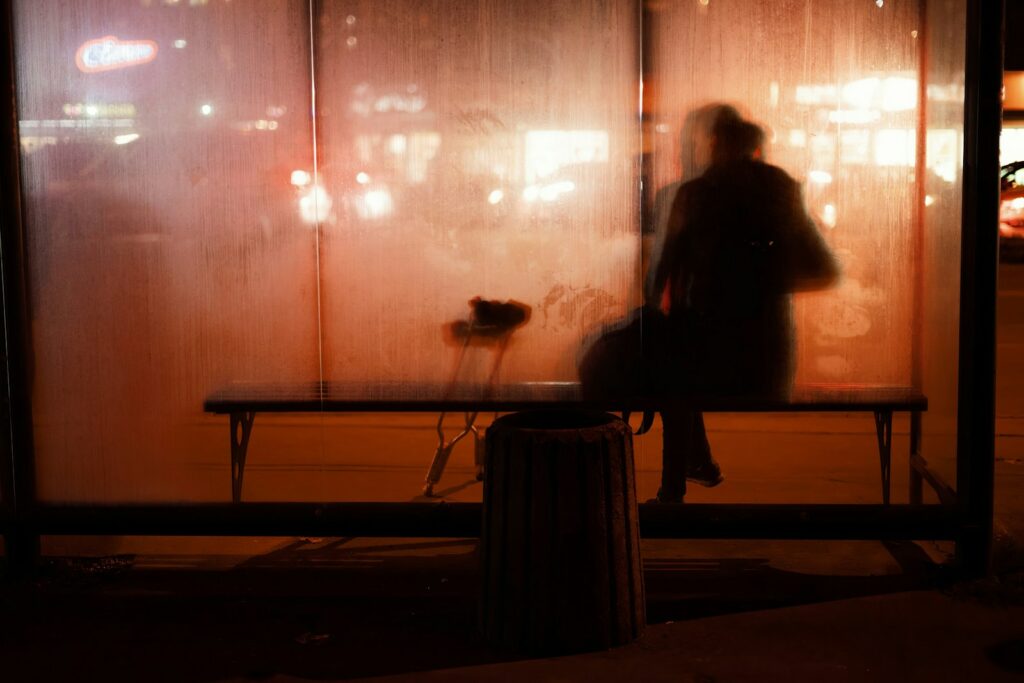 A person waits at a bus stop at night.
